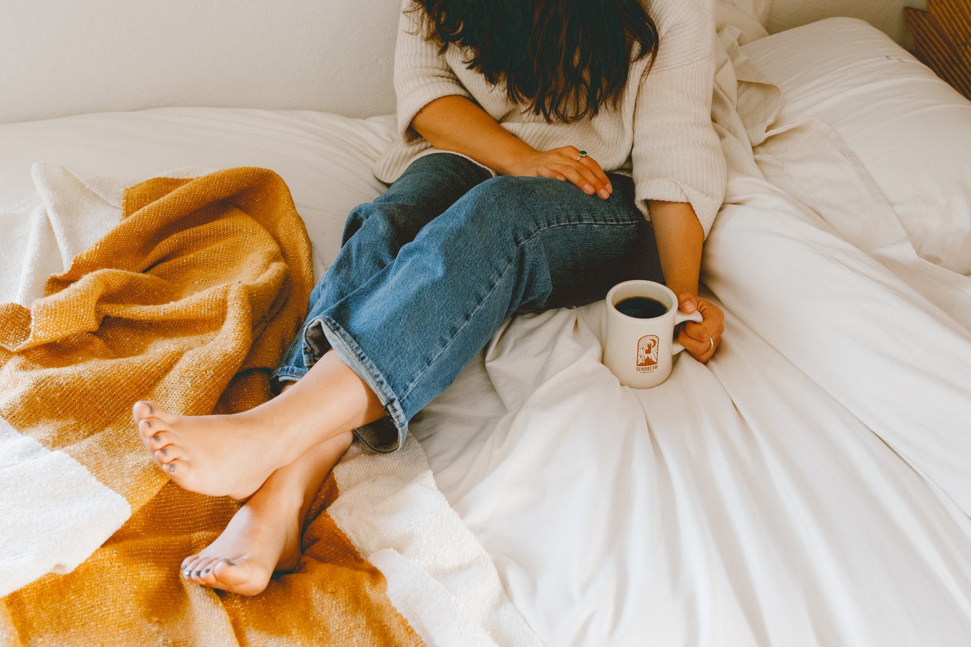 woman sitting on bed with golden throw